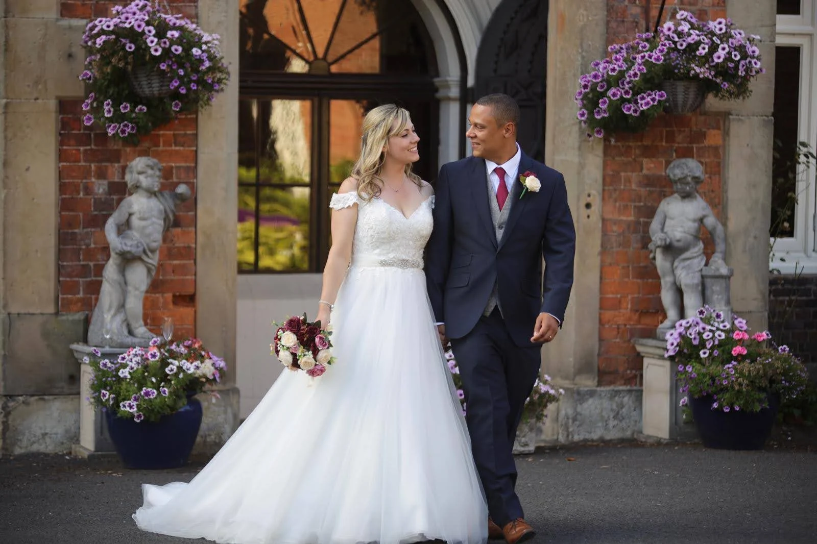 A wedding couple standing together outside a flower-filled venue