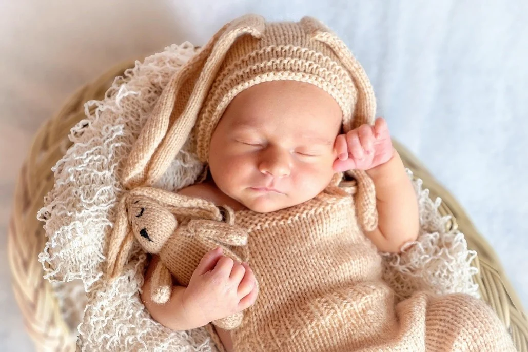 A sleeping baby cuddling a knitted rabbit